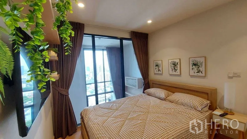 Condominium for rent in Watthana, Bangkok - Bright bedroom with large bed, balcony and floor-to-ceiling windows offering city views.