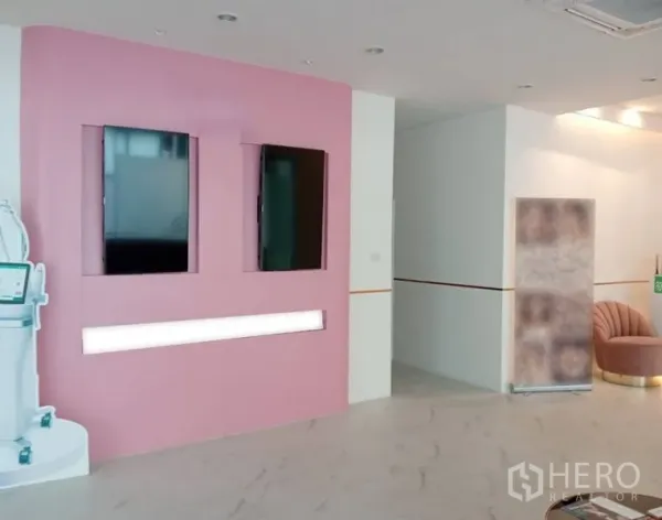 零售空间 出租在Watthana, Bangkok - 粉色展示墙，带嵌入式屏幕和氛围灯光。