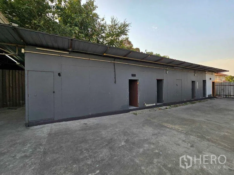 带办公室的家 出租在Prawet, Bangkok - 长条配套建筑，金属屋顶，旁为混凝土空地。