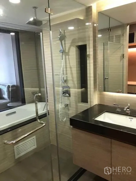 Condominium for rent in Pathum Wan, Bangkok - Contemporary bathroom with rain shower, bathtub by window and stone-top vanity.