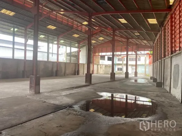店屋 出租在Yan Nawa, Bangkok - 开阔仓库内部，钢结构与混凝土地面，地面有积水。