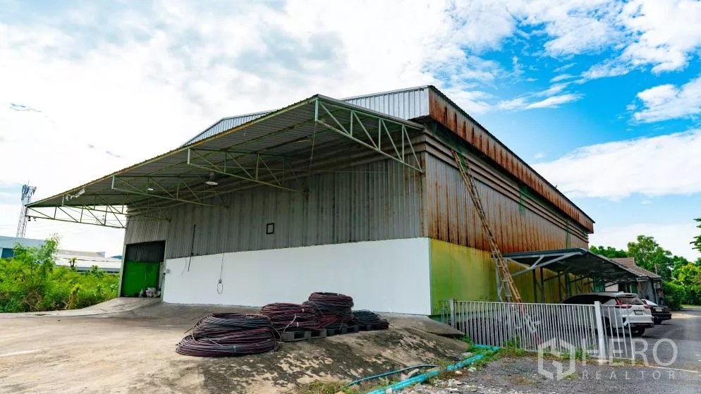 คลังสินค้า ให้เช่าในThanyaburi, Pathum Thani - มุมมองด้านข้างของโกดัง มีทางลาด คานหลังคาเหล็ก และประตูม้วนขนาดใหญ่ พร้อมลานกว้าง