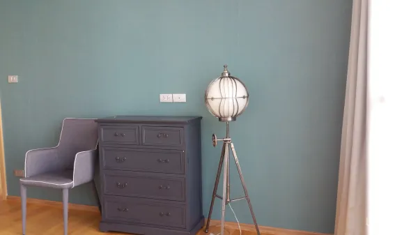 คอนโด ให้เช่าหรือขายในWatthana, Bangkok - มุมห้องนอนพร้อมตู้ลิ้นชักสีเทา เก้าอี้ผ้า และโคมไฟตั้งพื้นแบบขาตั้ง