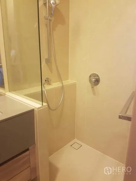 คอนโด ให้เช่าในWatthana, Bangkok - ห้องน้ำปูกระเบื้องสีเบจพร้อมพื้นที่อาบน้ำแบบกระจกกั้นและฝักบัวมือถือ
