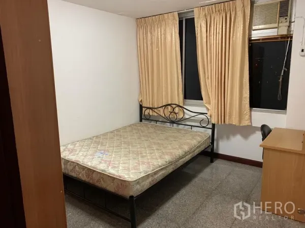 Condominium for rent in Sathon, Bangkok - Cozy bedroom with metal bed frame, desk, curtained window and wall AC unit.