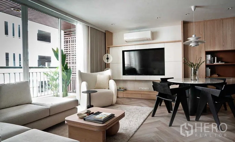 คอนโด ขายในRatchathewi, Bangkok - พื้นที่นั่งเล่นผนังทีวี โต๊ะทานข้าวทรงกลม และประตูออกระเบียงมีต้นไม้