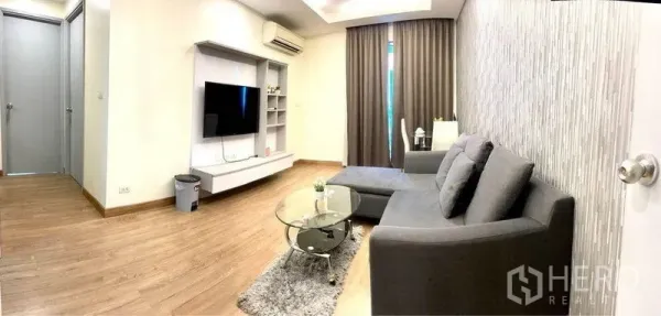 Condominium for rent in Huai Khwang, Bangkok - Open-plan living area with TV console, sectional sofa and floor-to-ceiling curtains.
