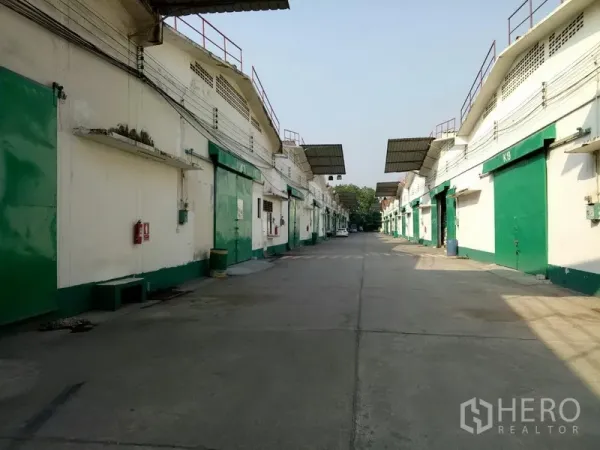 货栈 出租在Khlong Toei, Bangkok - 成排仓库外立面，绿色装卸门，宽阔内街便于卡车进出。