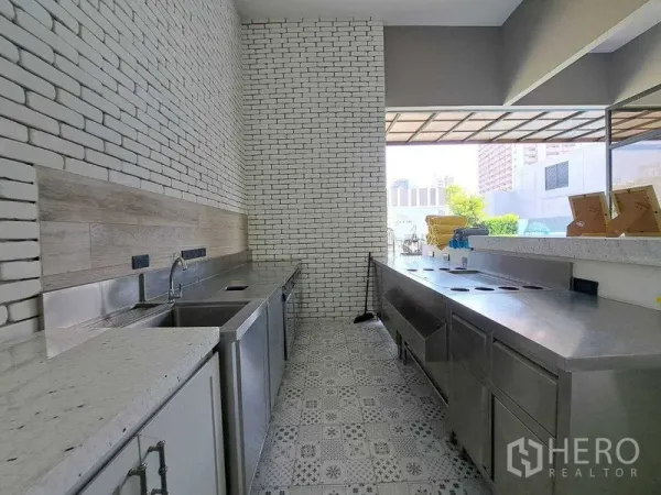 พื้นที่ขายปลีก ให้เช่าในWatthana, Bangkok - ครัวเตรียมอาหารเชิงพาณิชย์ เคาน์เตอร์สเตนเลส ผนังก่ออิฐสีขาว และพื้นกระเบื้องลาย