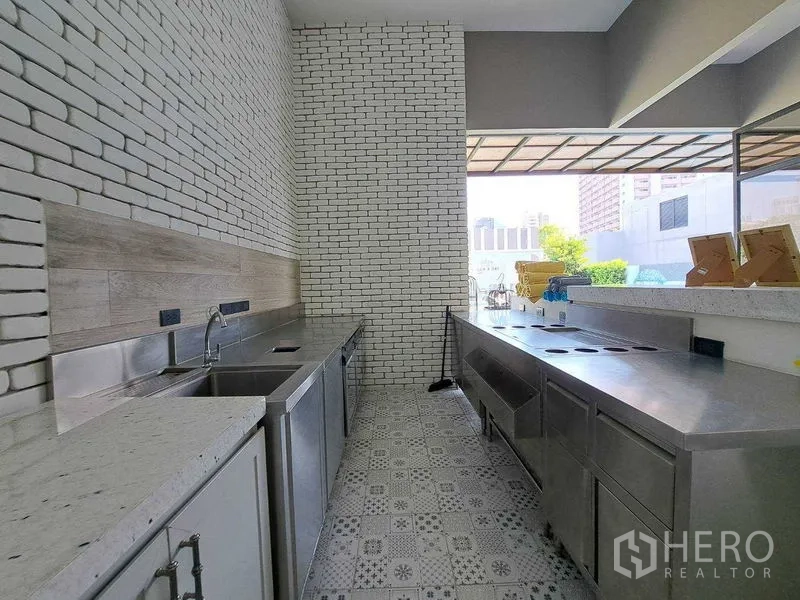 พื้นที่ขายปลีก ให้เช่าในWatthana, Bangkok - ครัวเตรียมอาหารเชิงพาณิชย์ เคาน์เตอร์สเตนเลส ผนังก่ออิฐสีขาว และพื้นกระเบื้องลาย