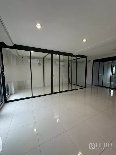 Home Office for rent - Empty tiled office floor with black-framed glass partitions and air-conditioners.