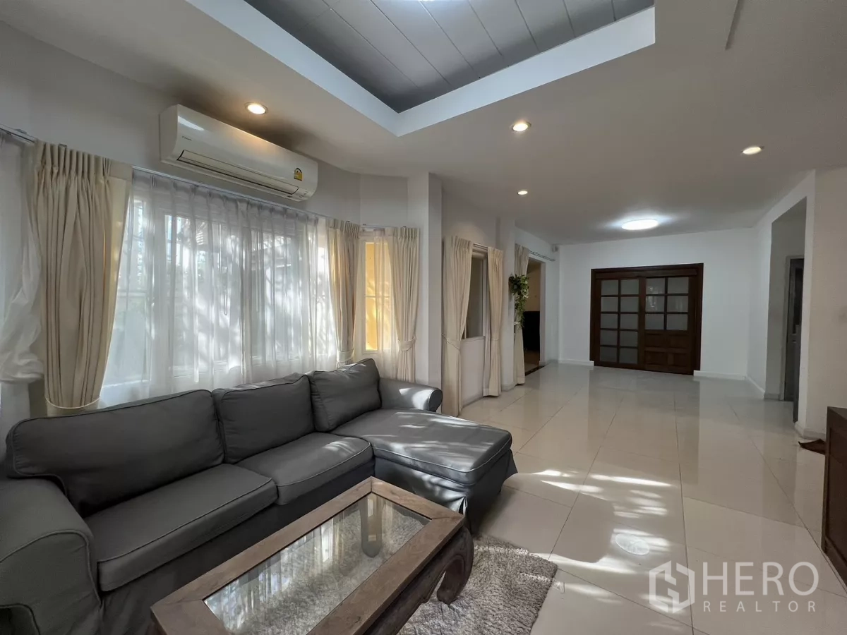 Detached House for rent in Bang Kapi, Bangkok - Sofa by large windows with air-conditioner and downlights.