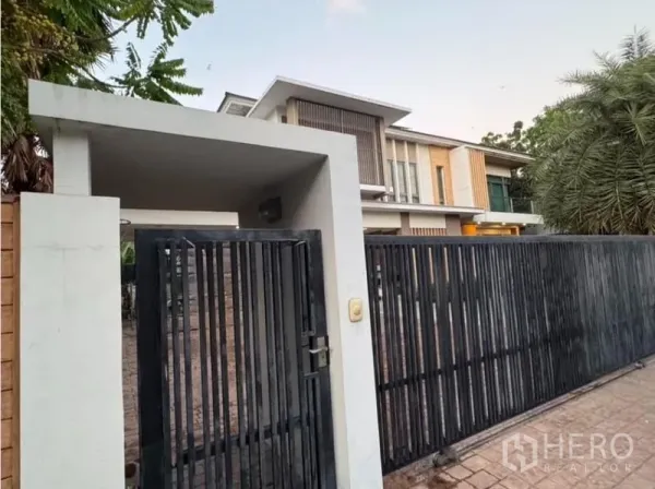独立式住宅 出售在Saphan Sung, Bangkok - 行人门与车道入口，竖条金属围栏的当代住宅