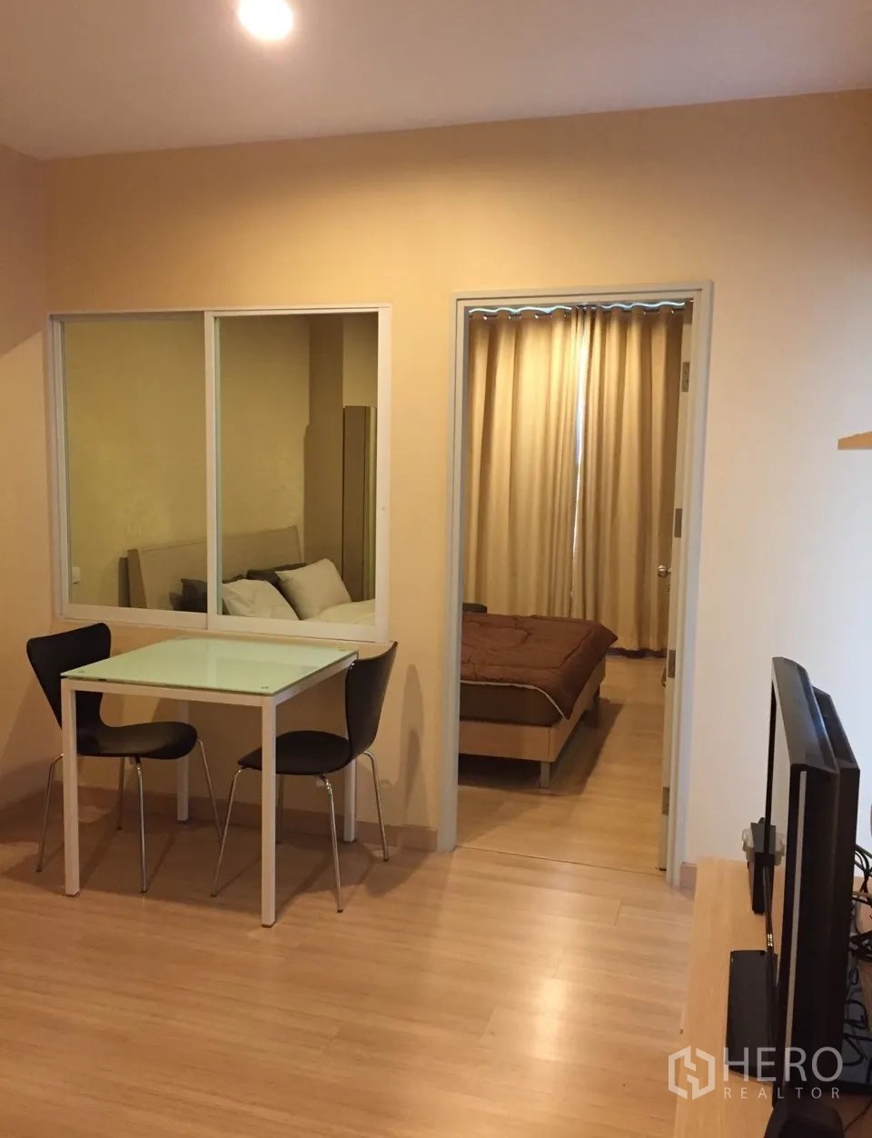 Condominium for rent in Bang Rak, Bangkok - Cozy living area with glass partition, dining table for two and a TV console in a 1-bedroom condo.