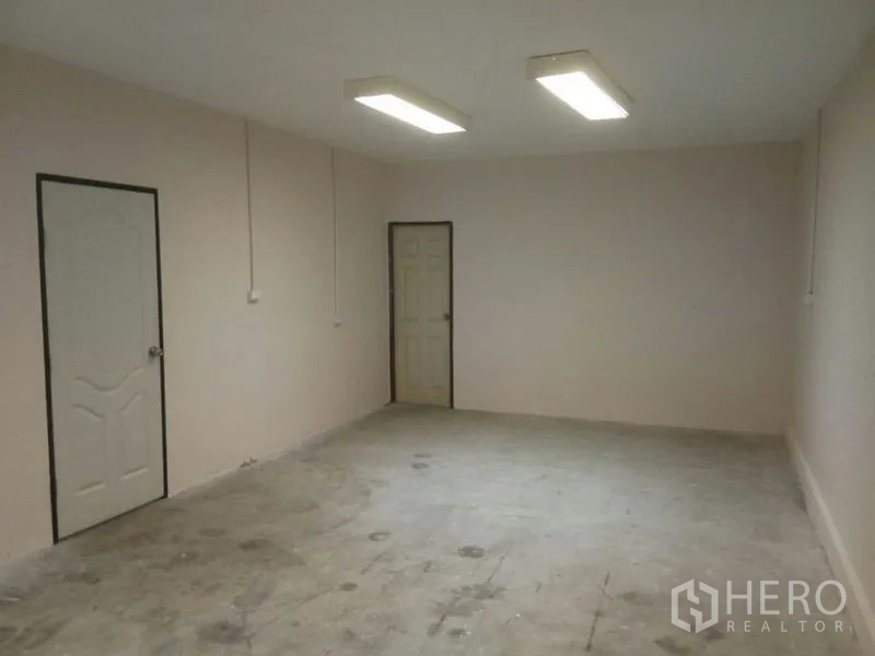 Warehouse for rent in Suan Luang, Bangkok - Large office space with two doors and bright ceiling fluorescent lighting.