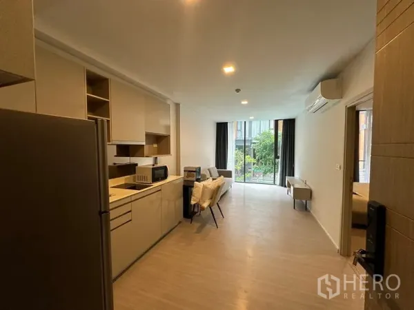 คอนโด ให้เช่าในKhlong Toei, Bangkok - พื้นที่ครัวและนั่งเล่นแบบโอเพ่นแพลน พร้อมโต๊ะทานอาหารและหน้าต่างบานใหญ่เห็นวิวสวน