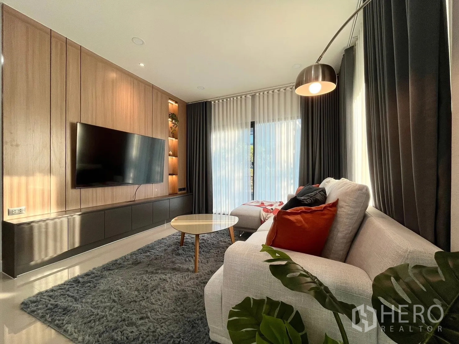 Detached House for rent in Bang Phli, Samut Prakan - Ground-floor living room with sectional sofa, large TV and floor-to-ceiling drapes.