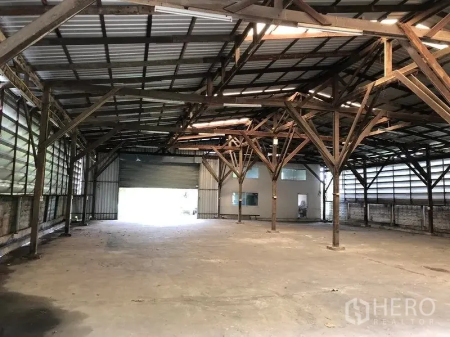 Warehouse for rent in Bang Bua Thong, Nonthaburi - Spacious warehouse interior with high steel roof, timber trusses and a wide roller shutter entry in Bang Bua Thong.
