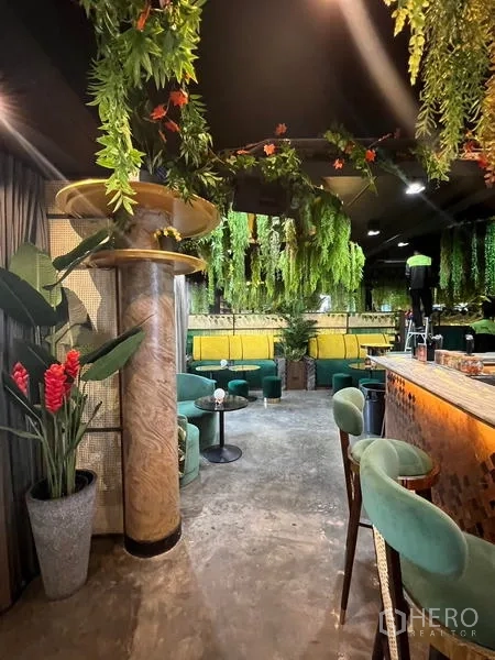 零售空间 出租在Watthana, Bangkok - 吧台一侧的绿沙发休闲区、装饰立柱与植物。
