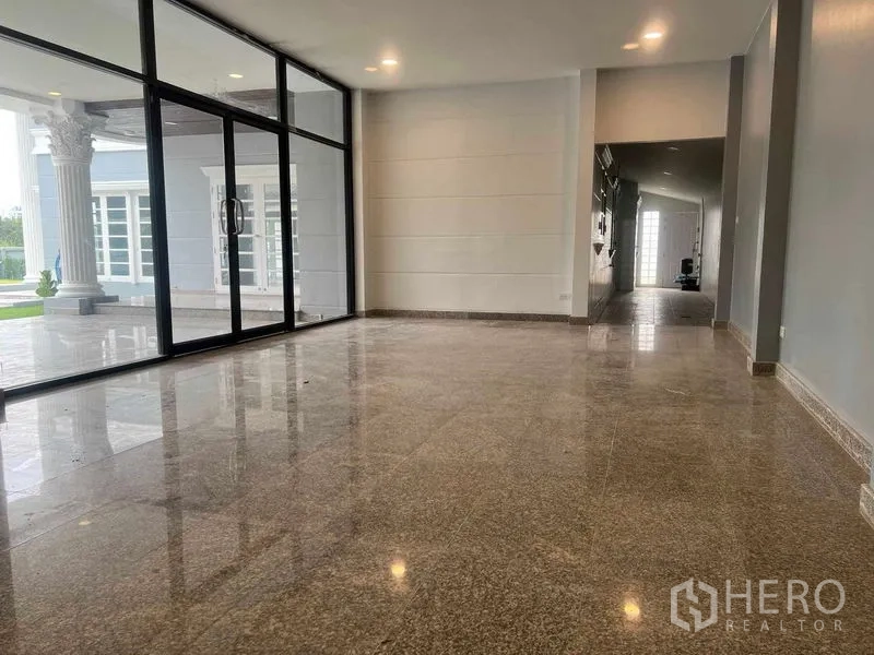 Detached House for sale in Bang Na, Bangkok - Bright living space with full-height glass wall opening to a patio with classical columns.