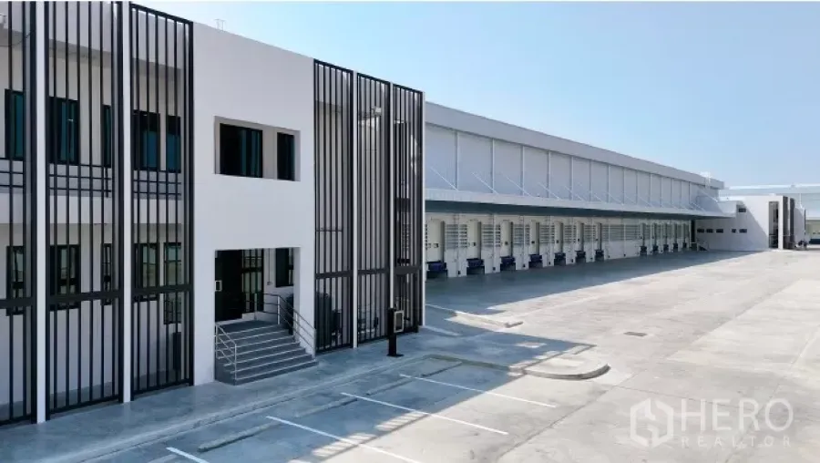 工厂 出租在Samut Prakan - 现代化厂房与办公楼立面，连续卸货月台与宽阔停车及作业场地