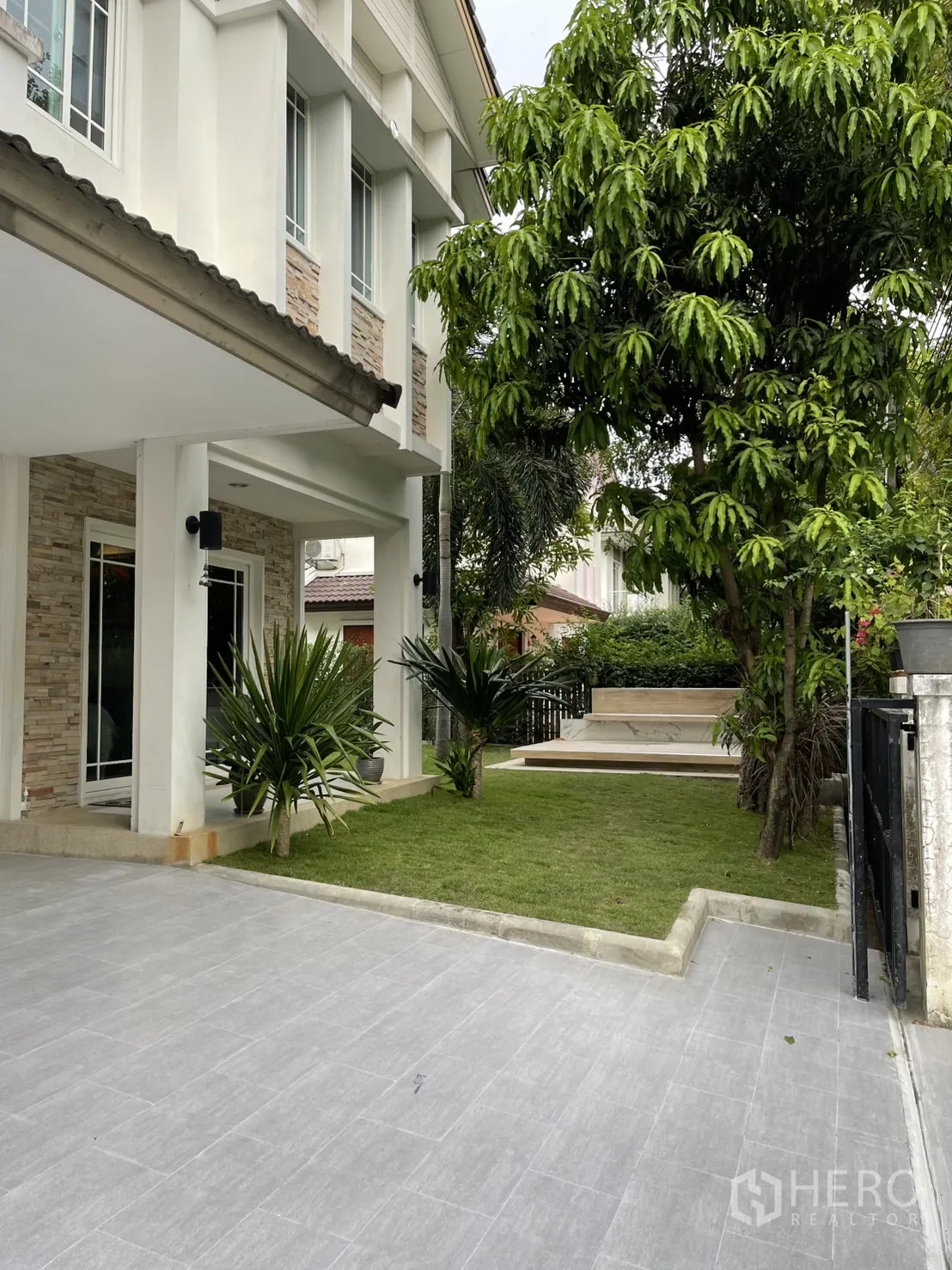 บ้าน ให้เช่าในBang Kapi, Bangkok - ลานจอดรถปูกระเบื้อง พร้อมสนามหญ้าหน้าบ้านและต้นไม้ใหญ่ข้างทางเข้า