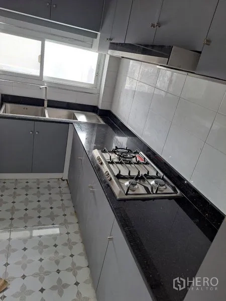 Detached House for rent in Prawet, Bangkok - Fitted kitchen with black granite countertop, gas hob and stainless sink by the window.