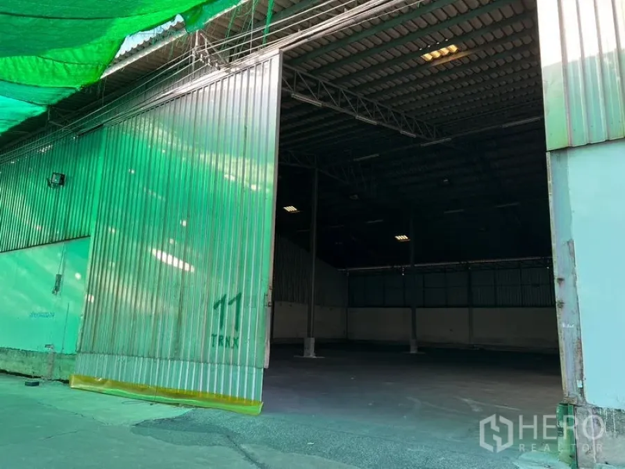 คลังสินค้า ให้เช่าในBang Sao Thong, Samut Prakan - ประตูเลื่อนโลหะขนาดใหญ่เปิดสู่โกดังหลังคาสูงพร้อมพื้นที่รับ-ส่งของมีแสลนบังแดด