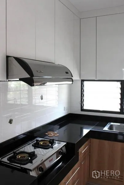 Detached House for rent in Prawet, Bangkok - Modern Thai kitchen with gas hob, range hood, black granite countertops and white cabinets.