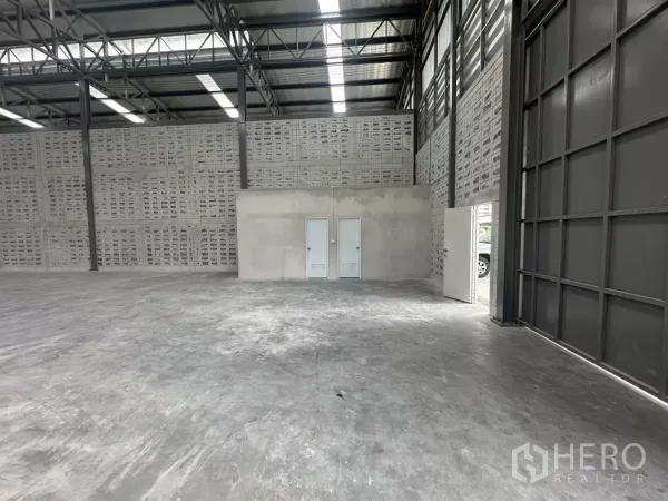 Warehouse for rent in Khlong Toei, Bangkok - Interior corner showing small utility rooms beside a large sliding metal door.