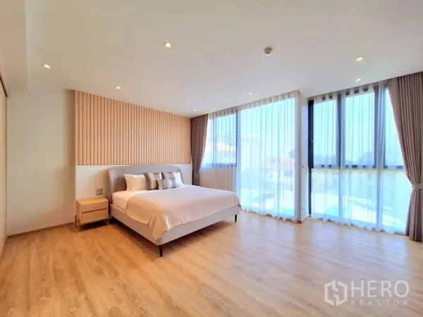 อพาร์ทเมนท์ ให้เช่าในBang Na, Bangkok - ห้องนอนใหญ่กว้าง เตียงคิง ไม้ตกแต่ง และหน้าต่างมุมพร้อมผ้าม่านโปร่ง
