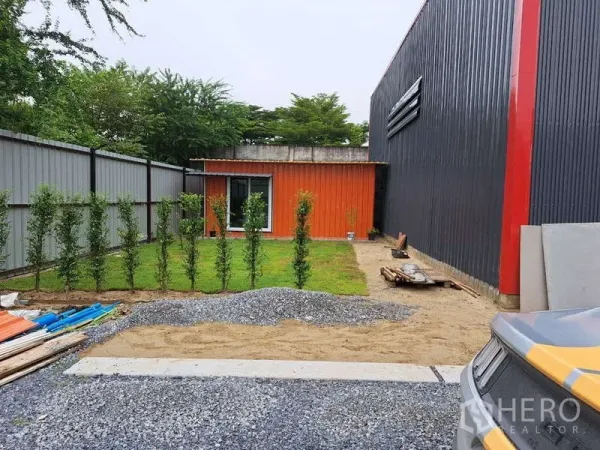 Warehouse for sale in Khlong Sam Wa, Bangkok - Small orange site office beside the warehouse with neat lawn, young hedge row and gravel walkway.