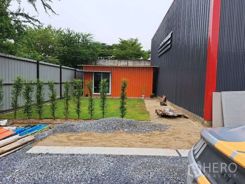 Warehouse for sale in Khlong Sam Wa, Bangkok - Small orange site office beside the warehouse with neat lawn, young hedge row and gravel walkway.
