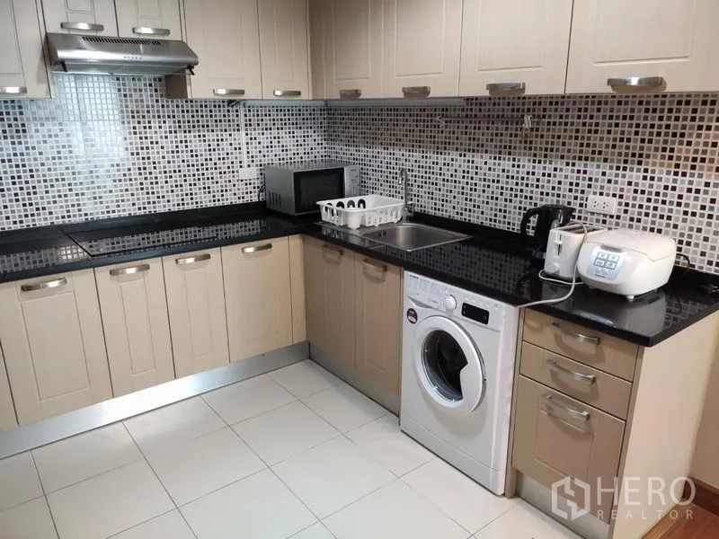 Condominium for rent in Huai Khwang, Bangkok - Fully fitted L-shaped kitchen with mosaic backsplash, black granite counters and washing machine.