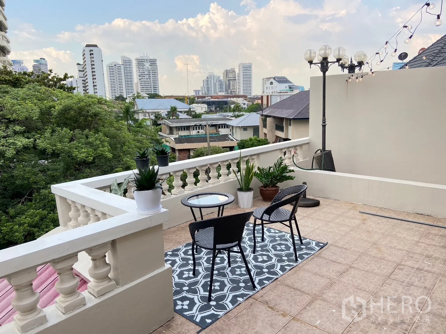 Home Office for rent in Watthana, Bangkok - Rooftop terrace with seating, city skyline views and string lights.