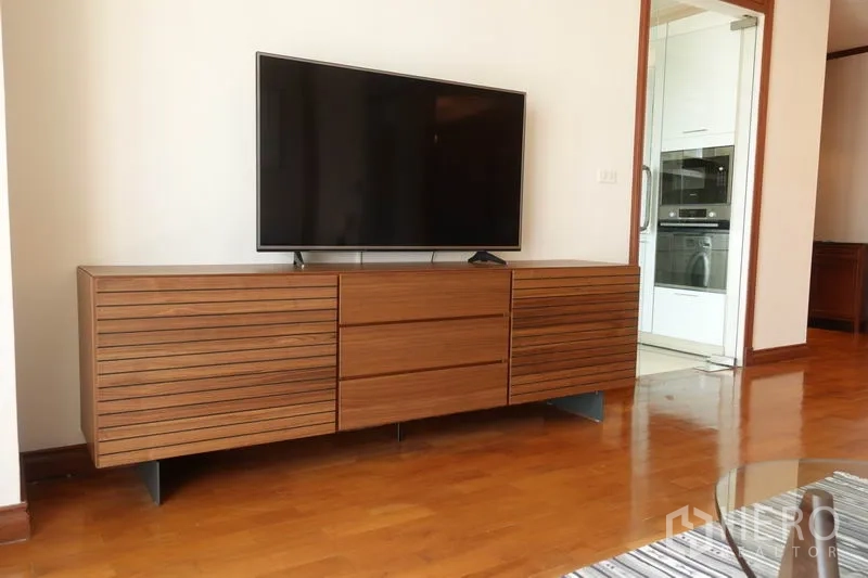 Condominium for rent in Khlong Toei, Bangkok - Close-up of flat-screen TV on a modern wood console in the living room.