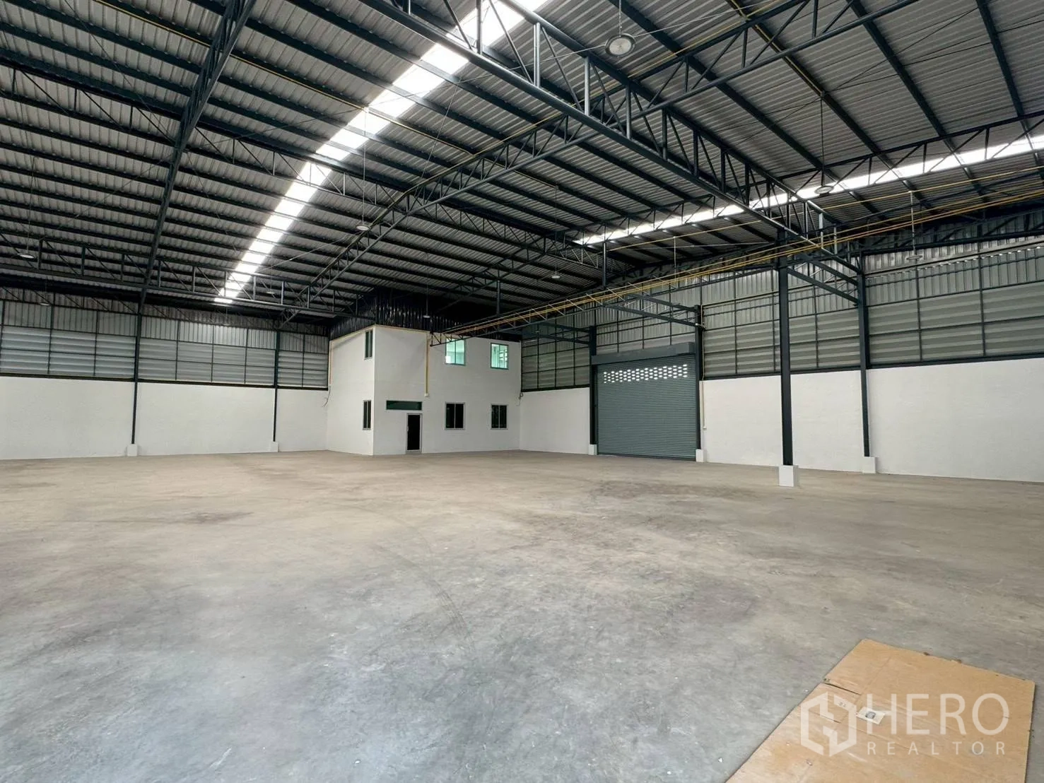 Warehouse for rent in Phutthamonthon, Nakhon Pathom - Open-span warehouse interior with high steel truss roof and roller shutter door.