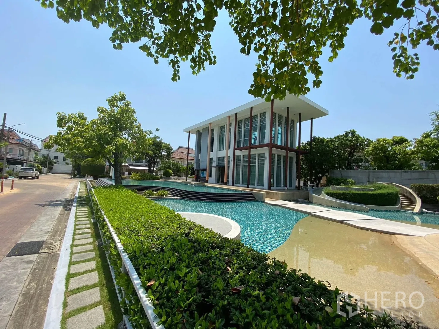 Detached House for rent in Mueang Samut Prakan, Samut Prakan - Modern clubhouse beside the pool amid landscaped greenery.