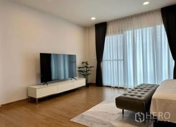 Detached House for rent in Bang Phli, Samut Prakan - Large master bedroom with TV console, bench and floor-to-ceiling sheer curtains opening to a balcony.
