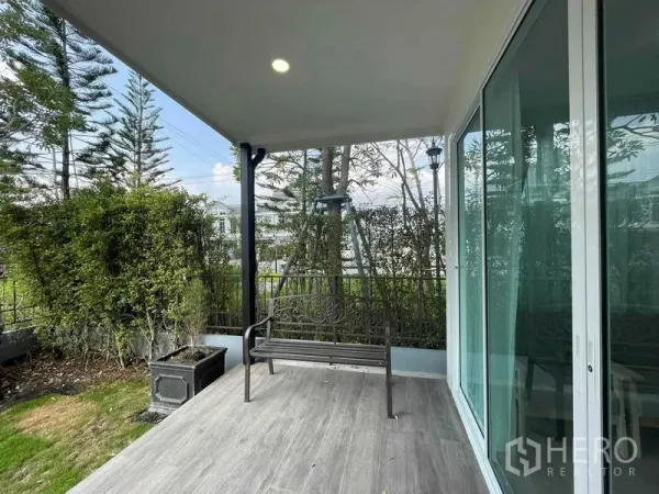 联排别墅 出租或出售在Prawet, Bangkok - 带顶露台配金属长椅，面向绿意花园与推拉玻璃门。