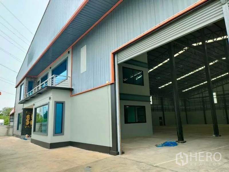 工厂 出租在Ban Phaeo, Samut Sakhon - 工厂外观，高卷闸门打开露出仓库内景。