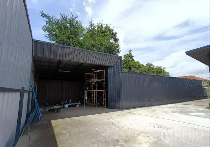 货栈 出租在Prawet, Bangkok - 黑色钢结构仓库正面，大开口入口与充足停车空间。