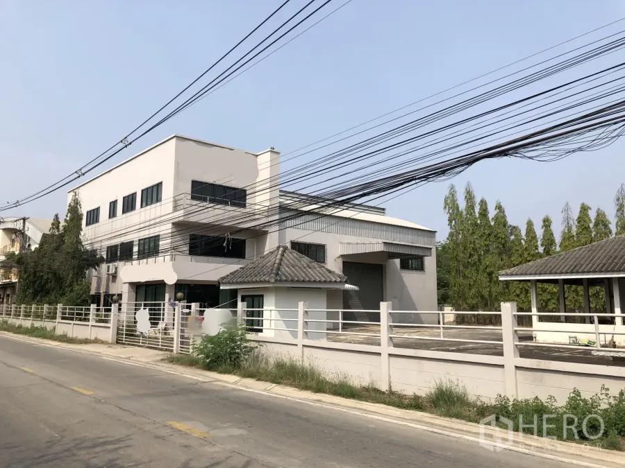 โรงงาน ขายในLam Luk Ka, Pathum Thani - มุมมองด้านหน้าโรงงานสมัยใหม่ มีอาคารสำนักงาน ลานโหลด และรั้วรอบริมถนนเงียบสงบ