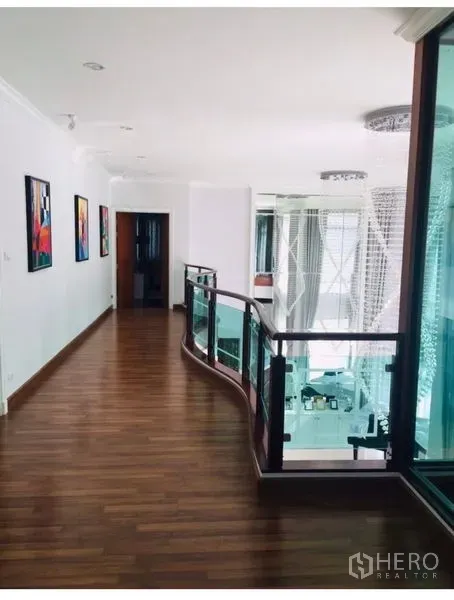 Detached House for sale in Saphan Sung, Bangkok - Upstairs corridor with curved glass balustrade overlooking a double-height living area.