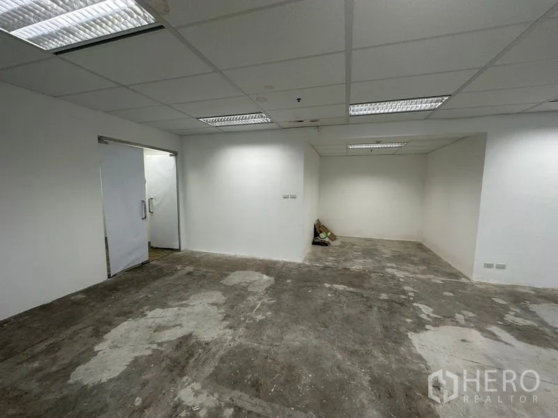 办公空间 出租 - 未装修的办公室，白色墙面、双开门、网格吊顶与日光灯，适合二次设计。