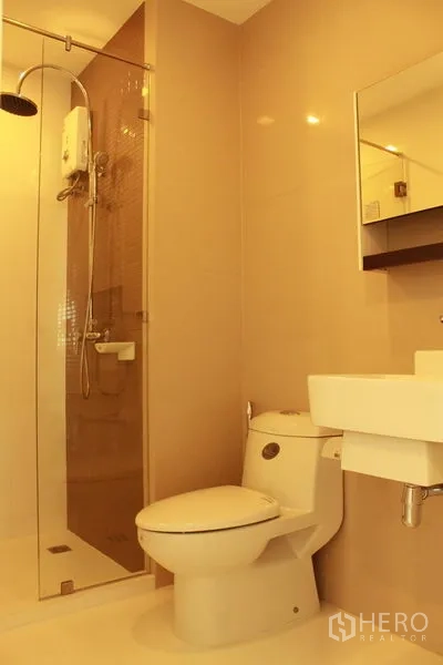 Condominium for rent or sale in Watthana, Bangkok - Bathroom featuring a glass-enclosed shower with rain head, toilet, and wall-mounted sink.