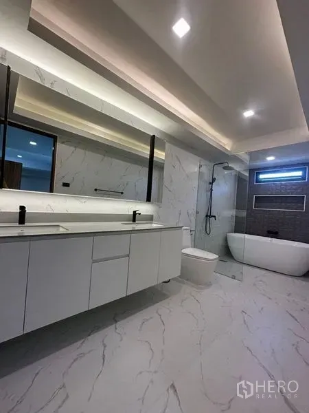 Detached House for rent in Suan Luang, Bangkok - Spacious master bathroom with double vanity, freestanding tub and glass shower in marble finish.