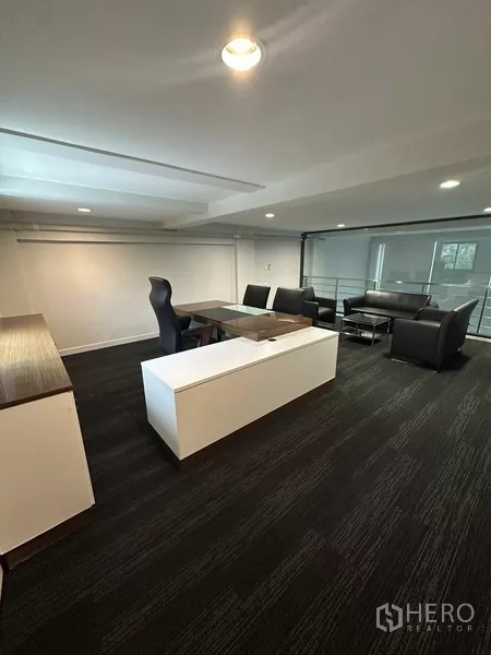 Home Office for rent - Mezzanine executive workspace with desk and sofa set on dark carpet.