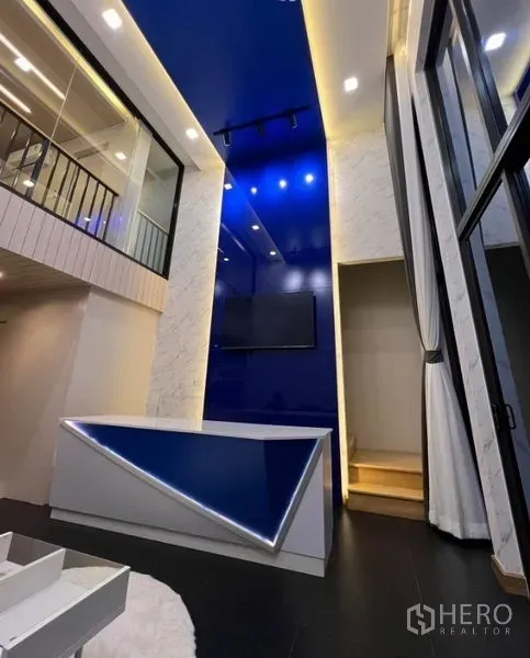 联排别墅 出租在Thanyaburi, Pathum Thani - 挑高客厅，蓝色特色墙体、LED灯带吧台与玻璃栏杆夹层