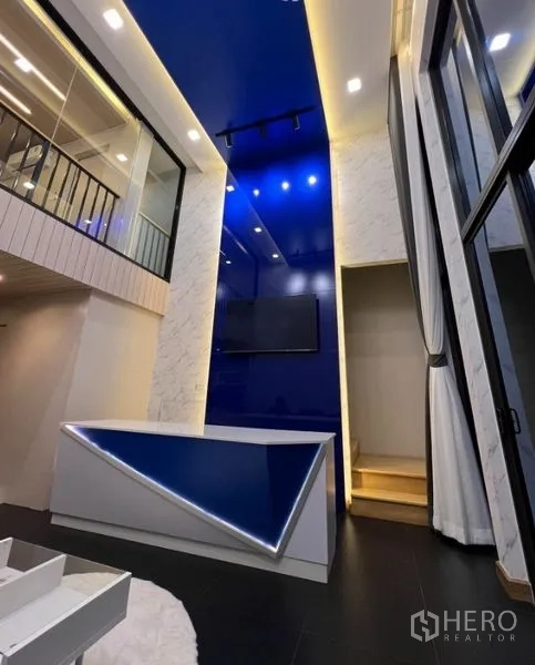 联排别墅 出租在Thanyaburi, Pathum Thani - 挑高客厅，蓝色特色墙体、LED灯带吧台与玻璃栏杆夹层